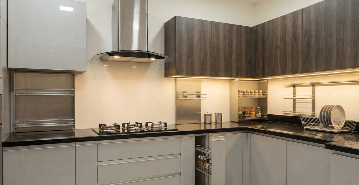 A modern modular kitchen interior in Bangladesh featuring high-gloss cabinets, stainless steel chimney hood, integrated storage accessories, granite countertop, and LED lighting, exemplifying a premium home upgrade.
