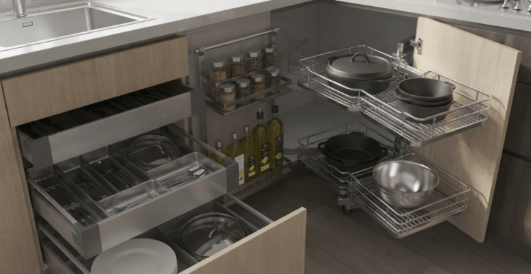 A close-up view of installed modular kitchen accessories in BD, showcasing a chrome corner pull-out system and stainless steel drawer baskets fully stocked with cookware.